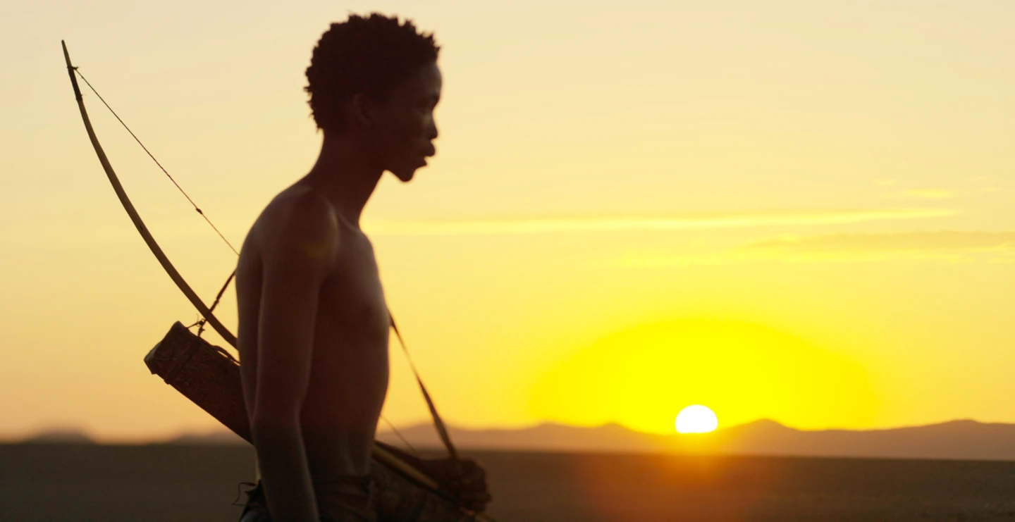 A man with a bow and arrow in the desert.